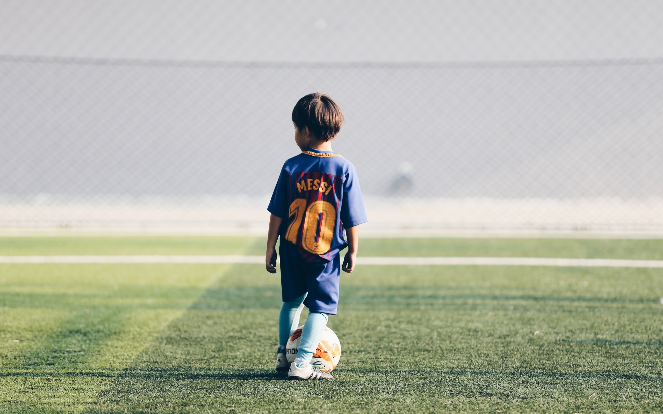 Мальчик футболист с мячом на поле