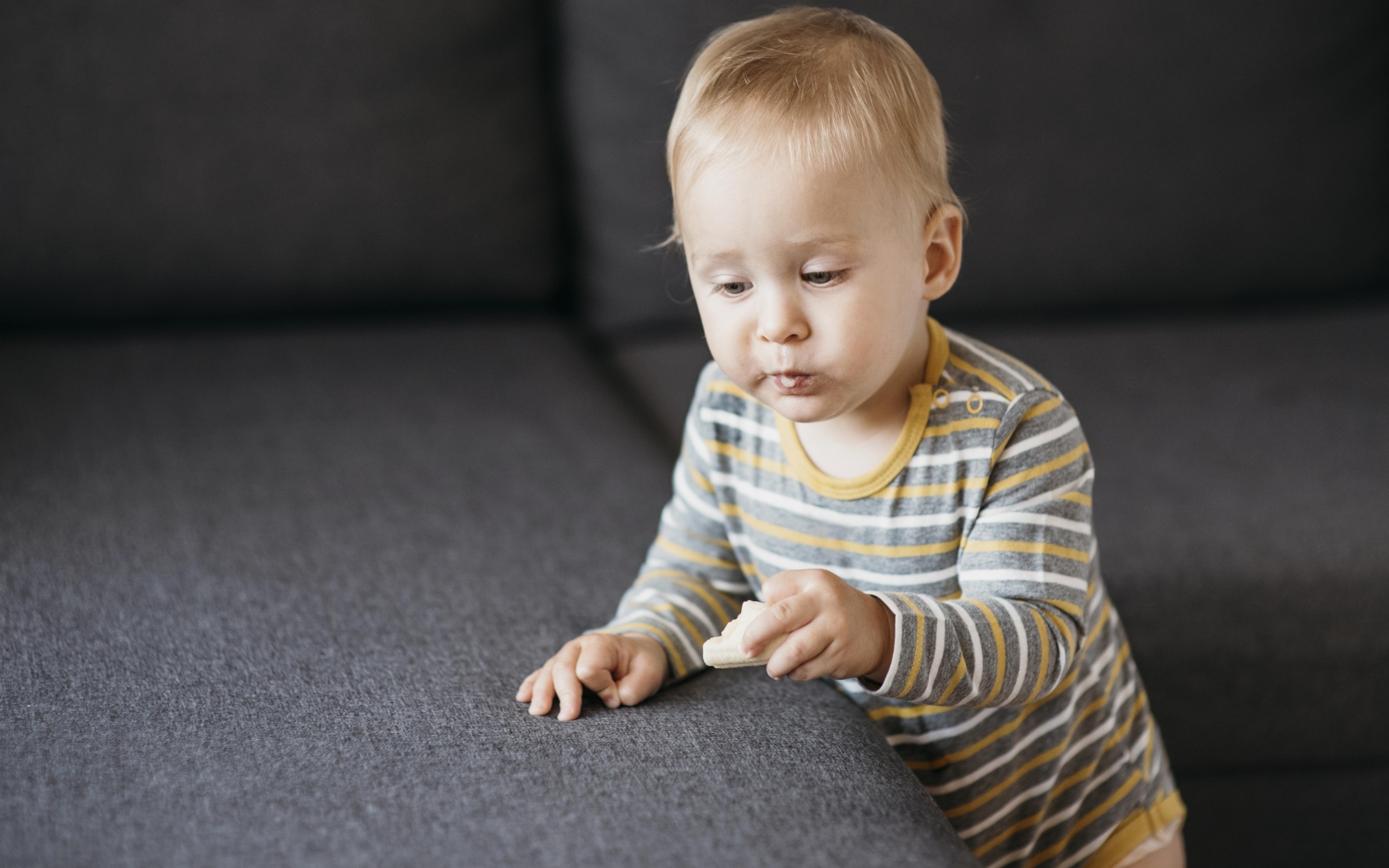 Любопытный маленький ребенок у дивана