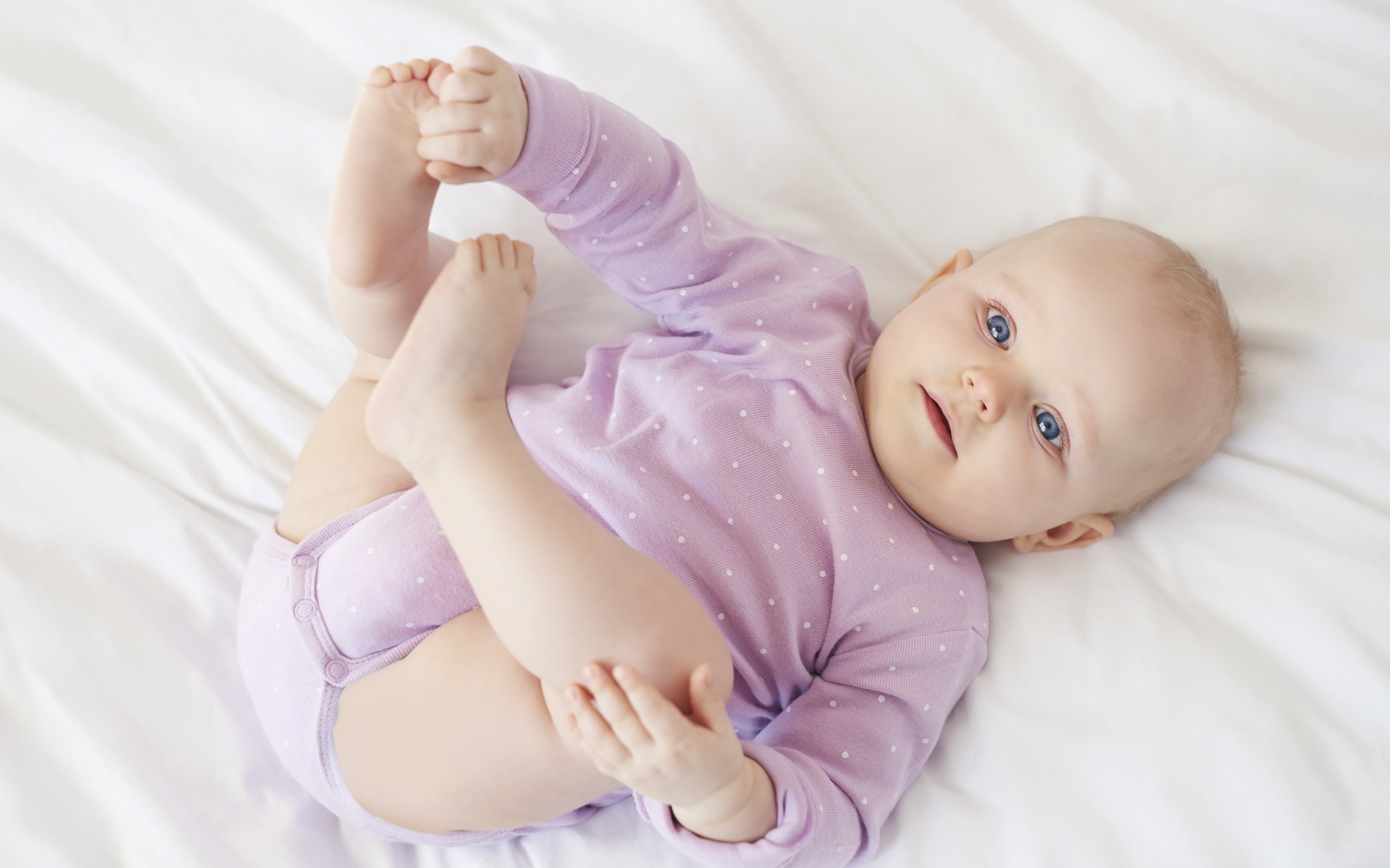 Милый голубоглазый малыш на белом покрывале