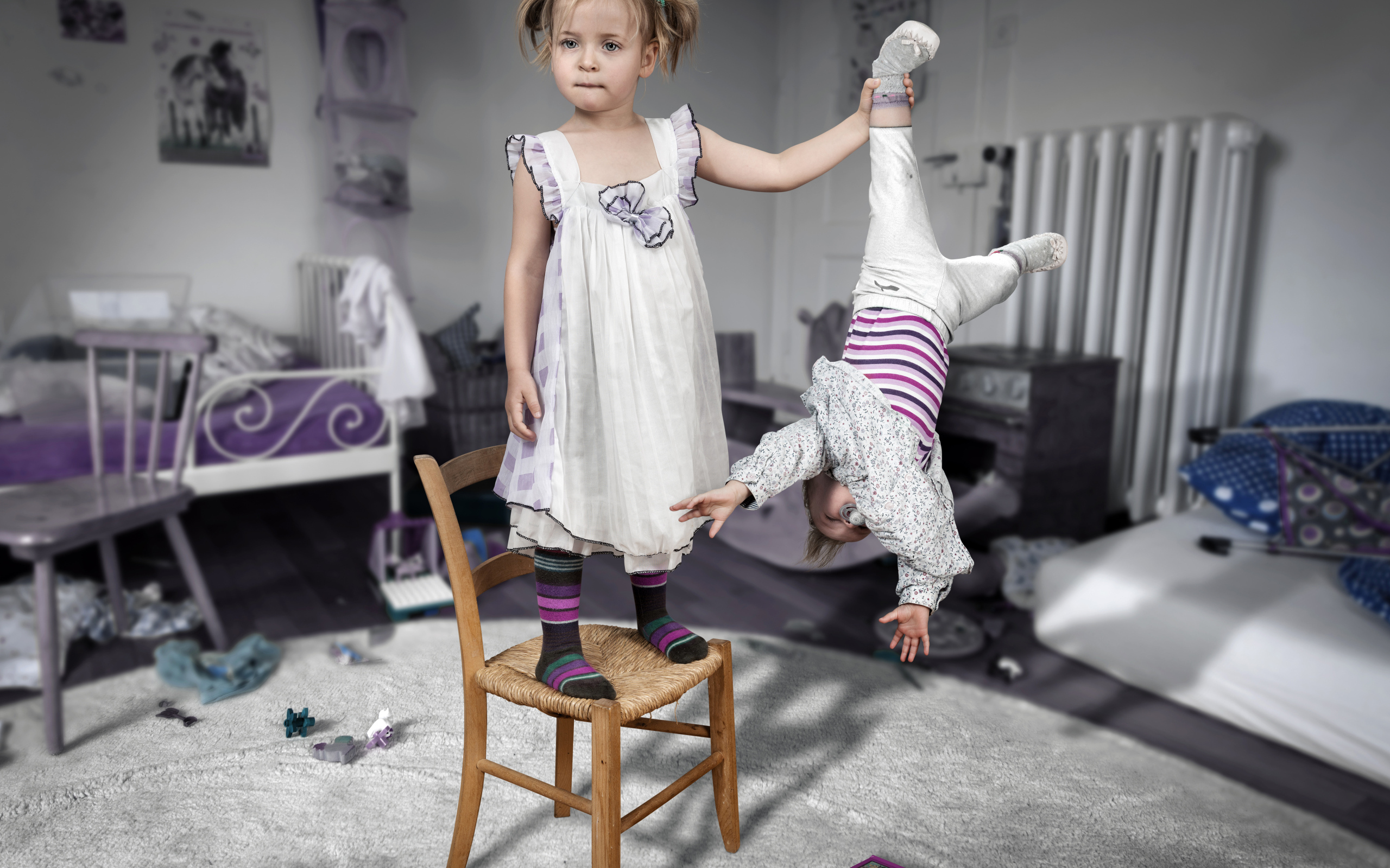 Девочка держит маленького брата за ногу