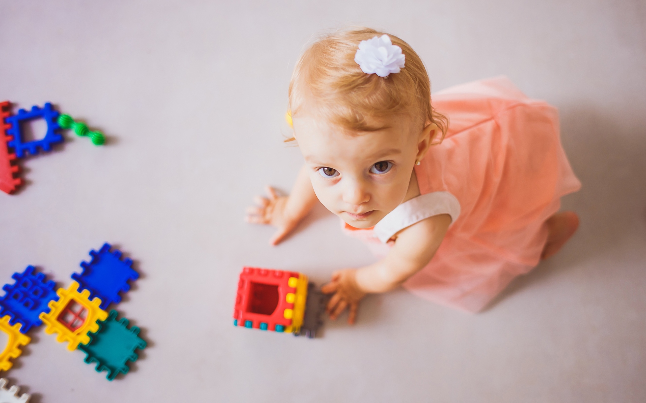 Маленькая девочка играет на полу с конструктором