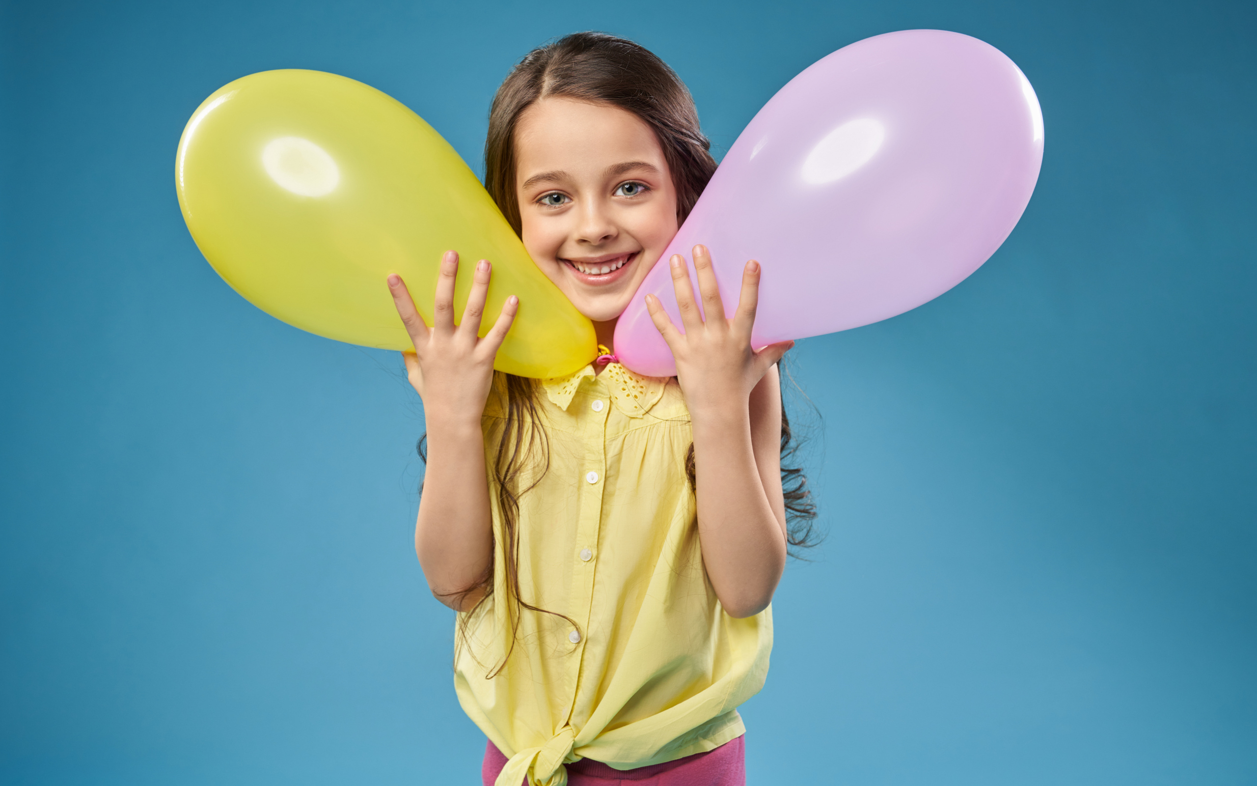 Маленькая девочка с воздушными шариками на голубом фоне
