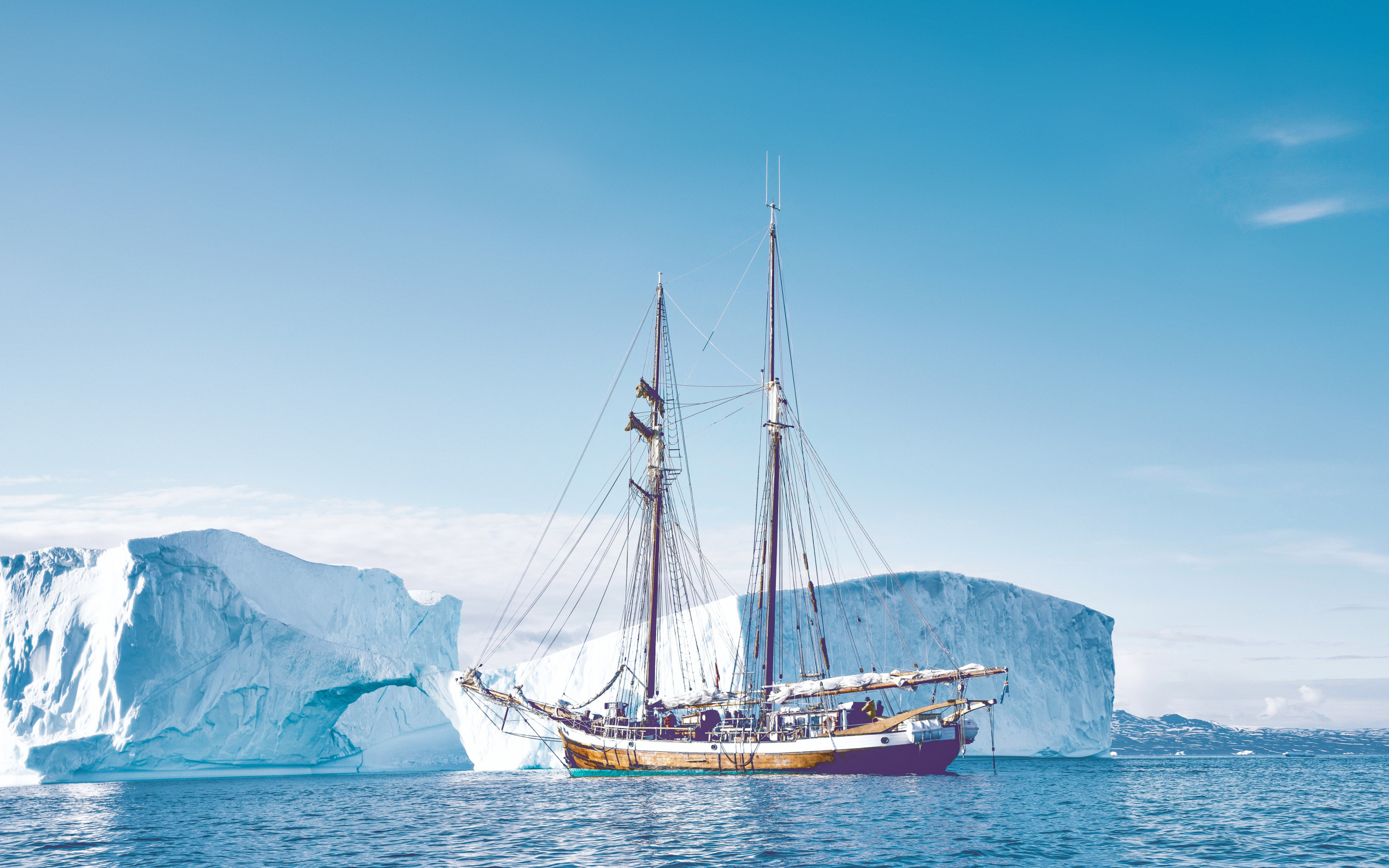 Большой корабль подплывает к голубому айсбергу в море