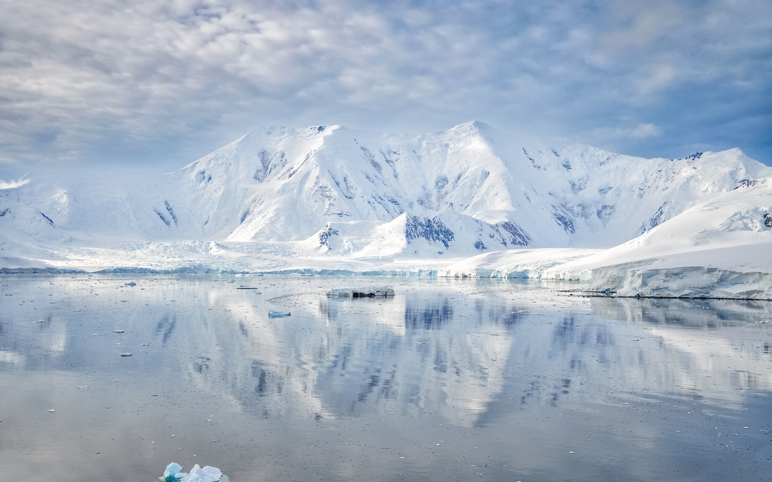 Заснеженные горы под белыми облаками у океана, Антарктида 