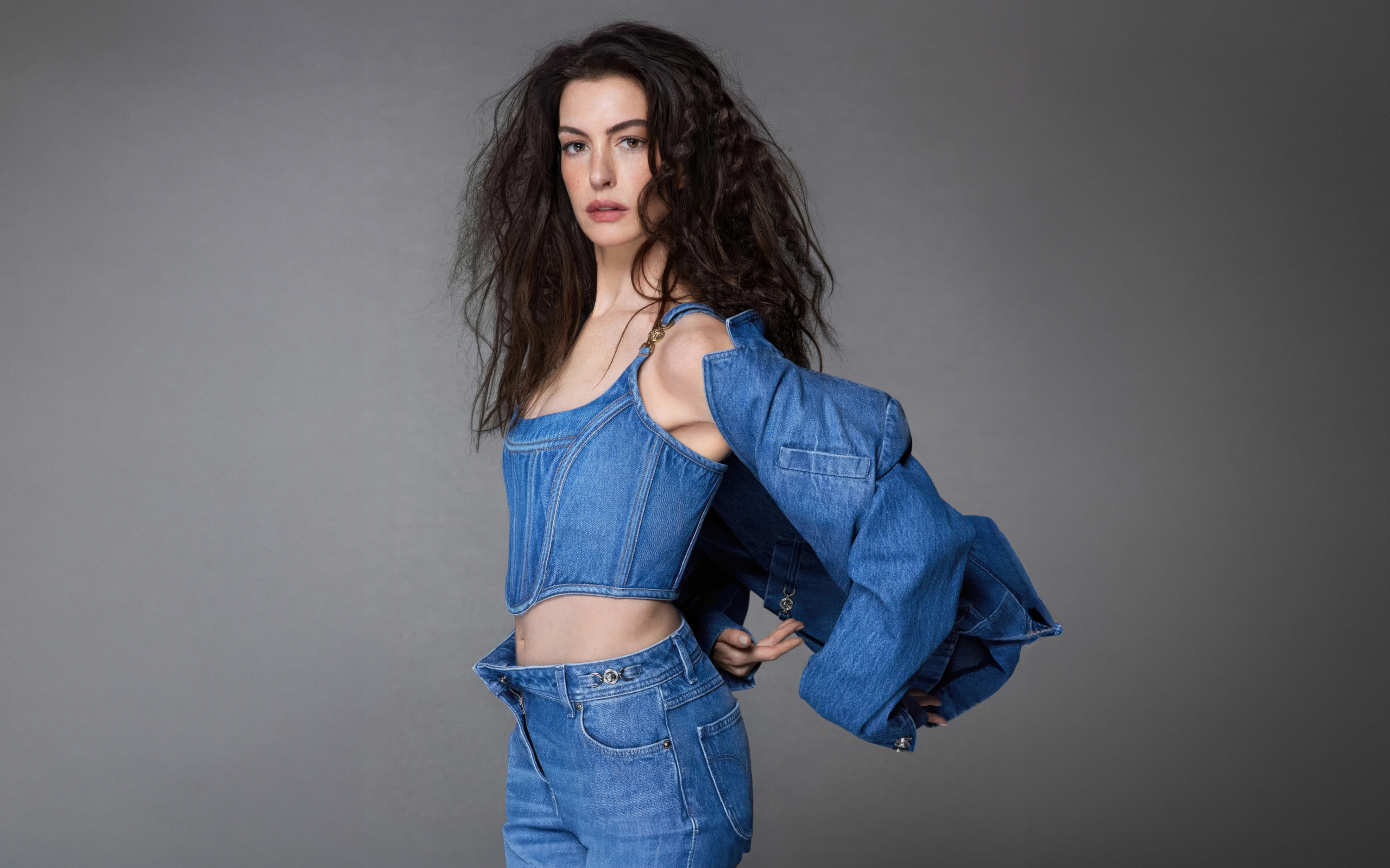 Актриса Энн Хэтэуэй в джинсовом костюме на сером фоне