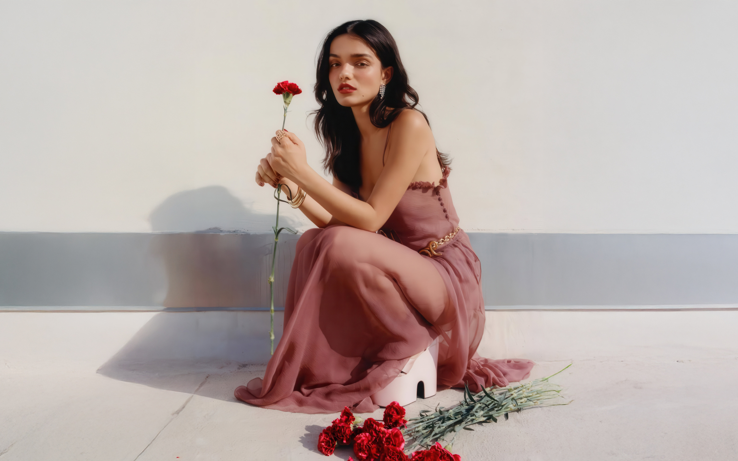 Актриса Рэйчел Зеглер с красными гвоздиками сидит на полу
