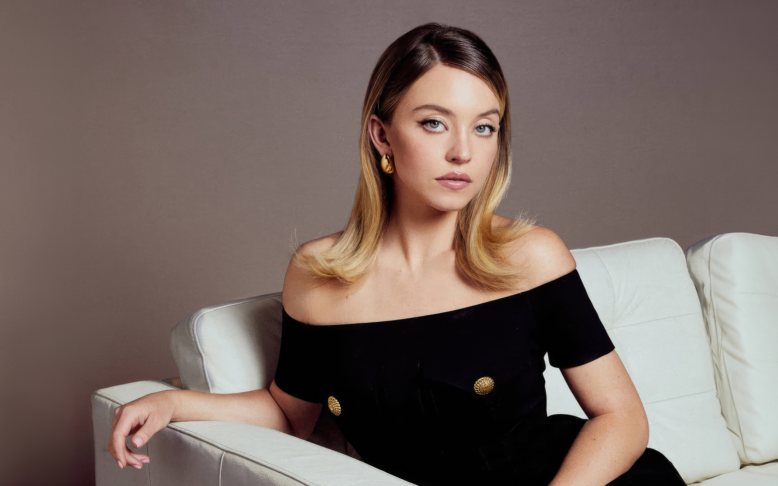 Актриса Сидни Суини в черном платье на белом диване