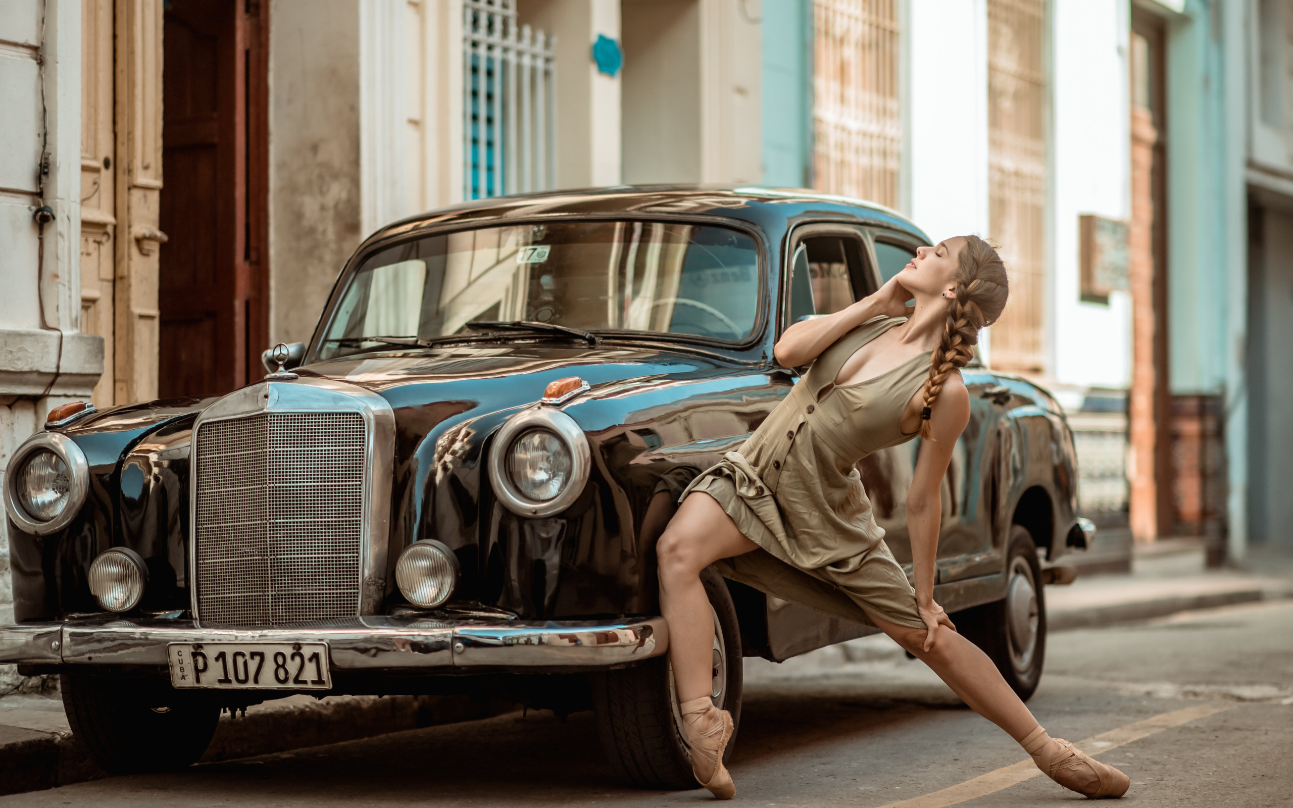 Девушка балерина стоит у старой машины