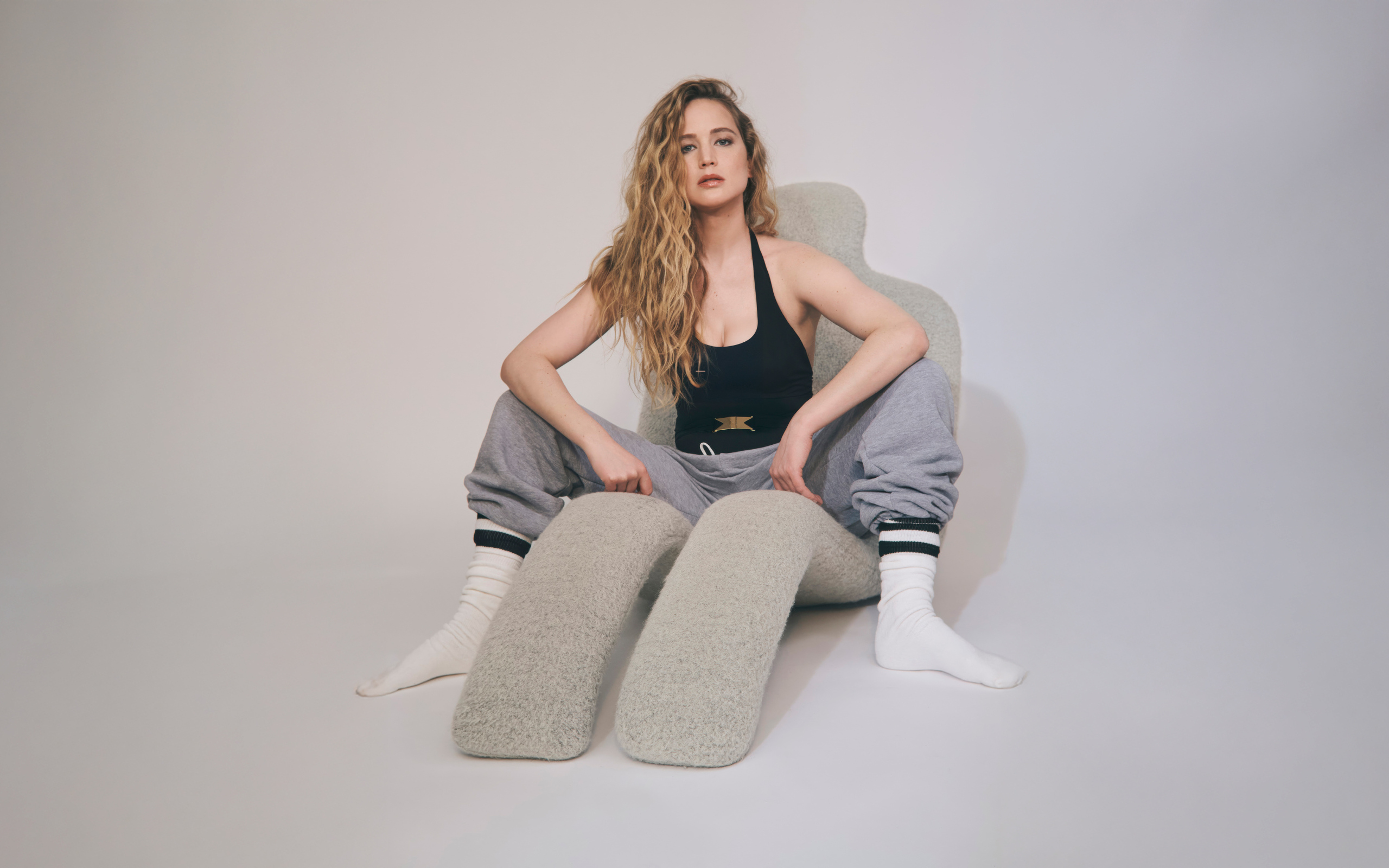 Красивая актриса Дженнифер Лоуренс  сидит на сером кресле