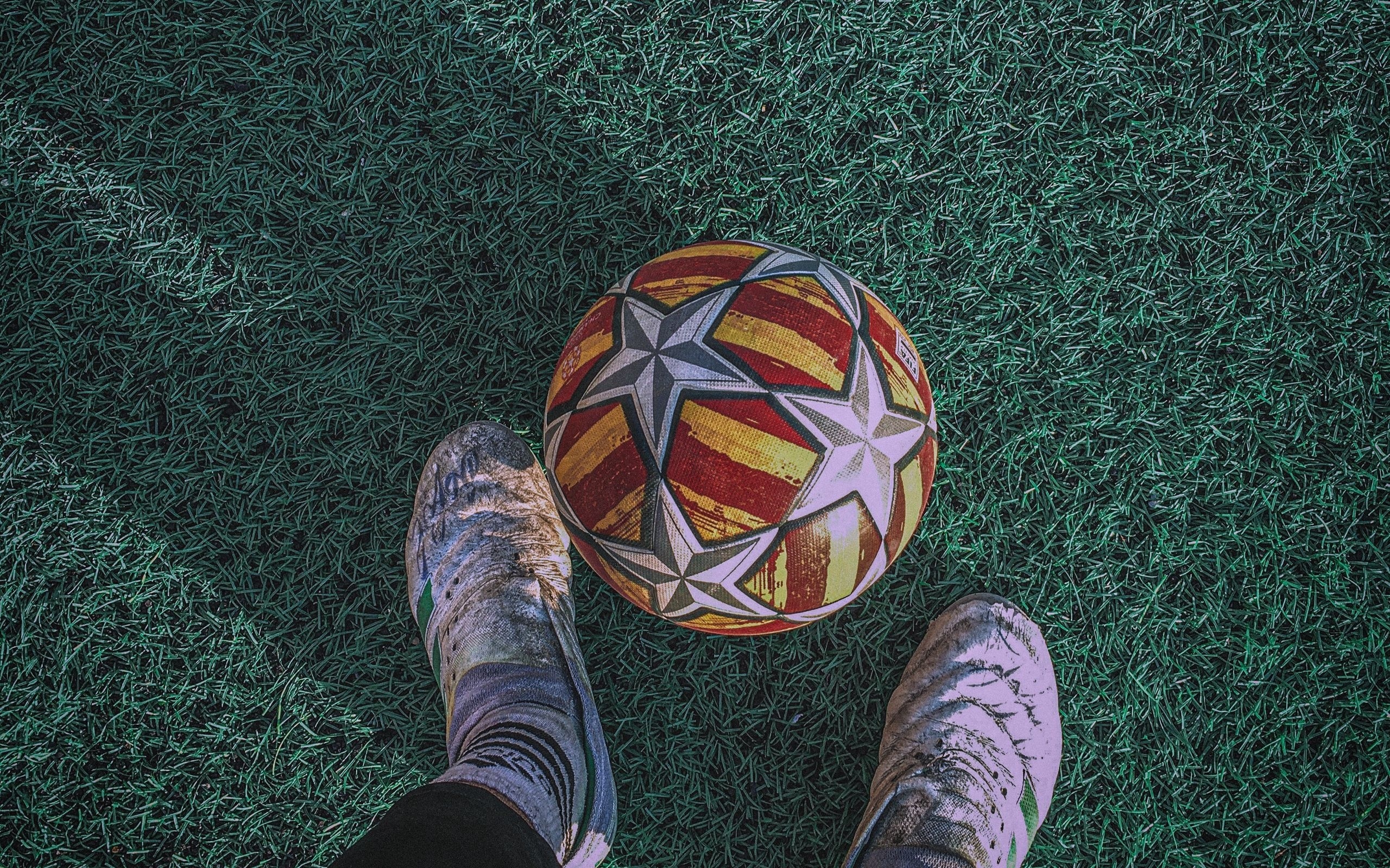 Футбольный мяч на зеленом поле с ногами футболиста