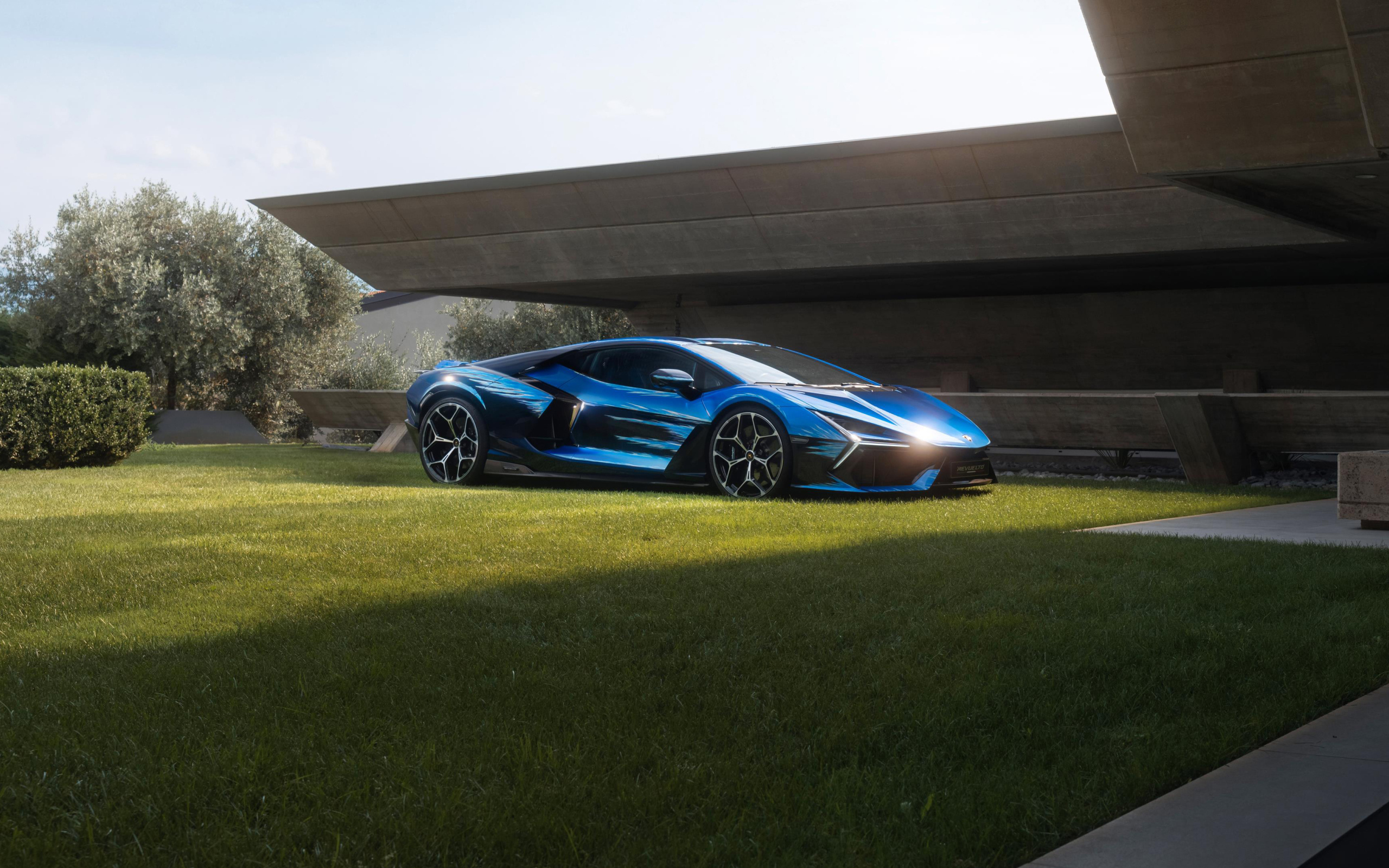 Синий Lamborghini Revuelto Opera Unica 2024 года на зеленой траве