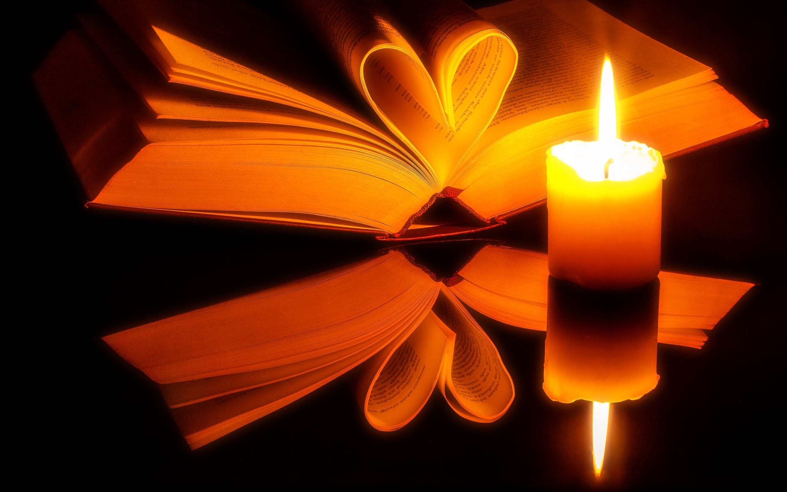 Открытая книга с зажженной свечой отражаются в черной поверхности