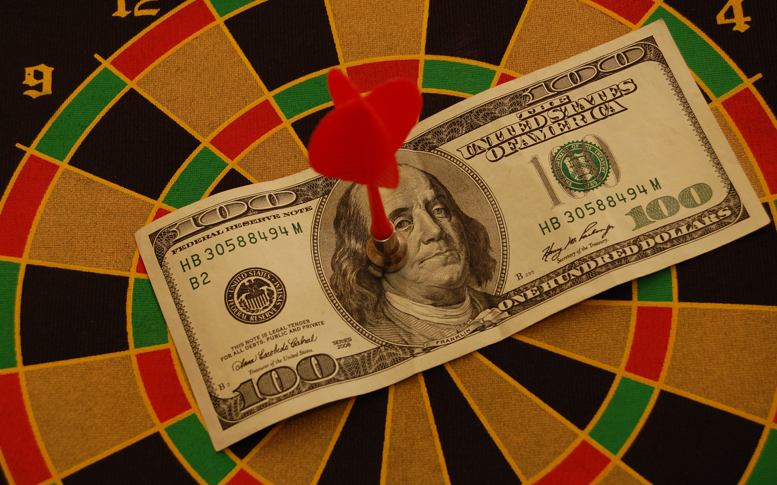 Купюра сто долларов на доске для дартс