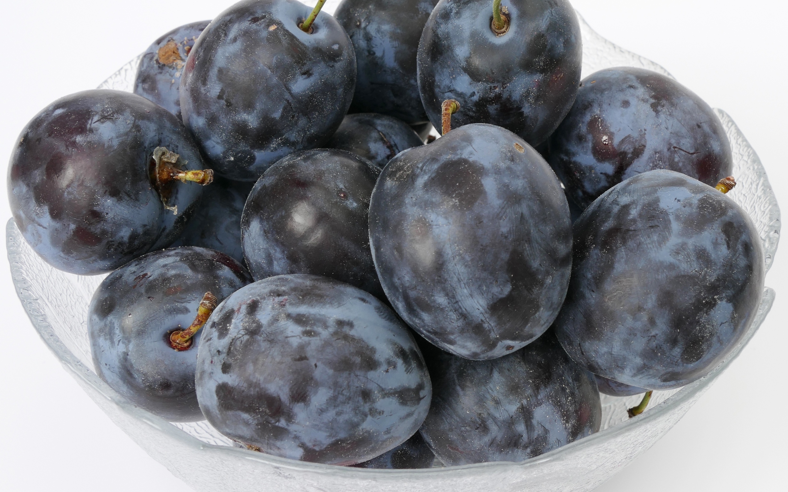 Стеклянная тарелка с вкусными синими сливами