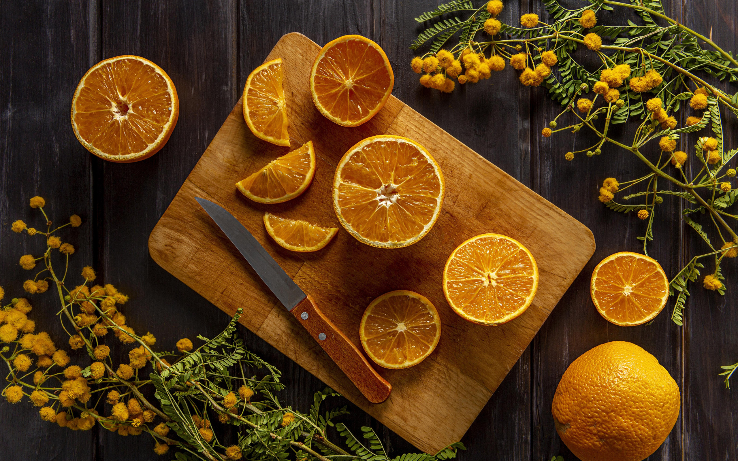 Нарезанный апельсин на доске на столе с цветами