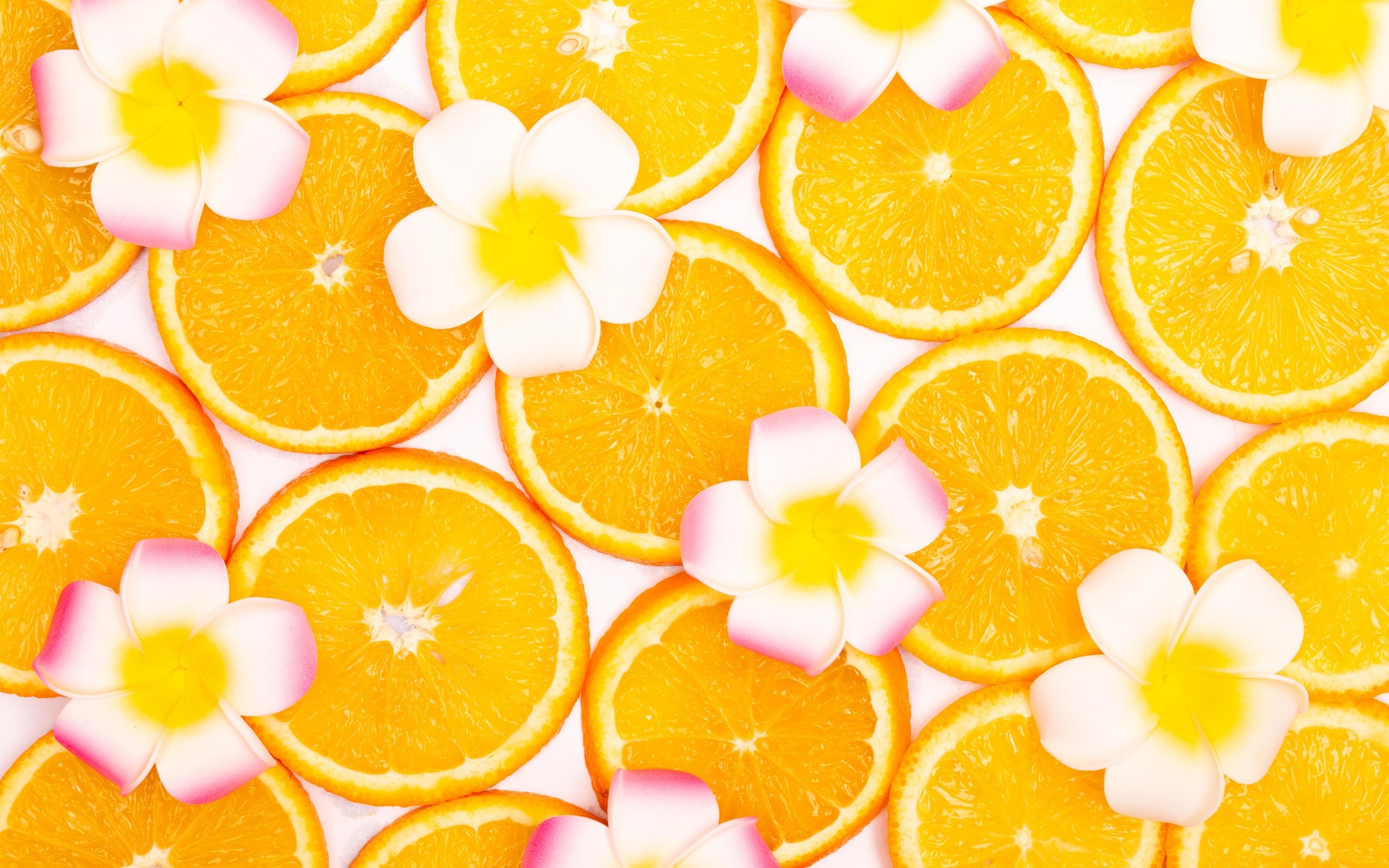 Нарезанный апельсин с цветами плюмерии для фона