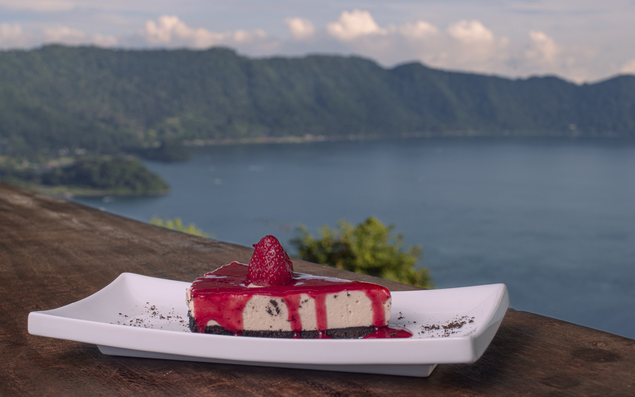 Кусок чизкейка с клубничным джемом на фоне моря