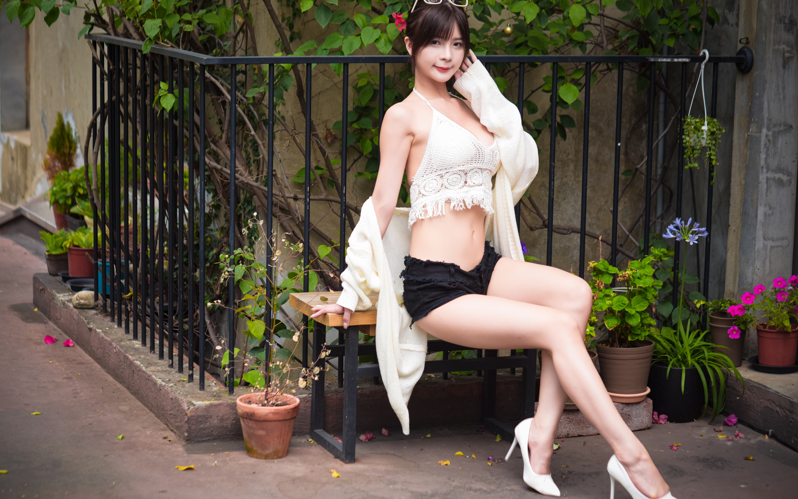 Стройная девушка азиатка сидит на лавке у дома