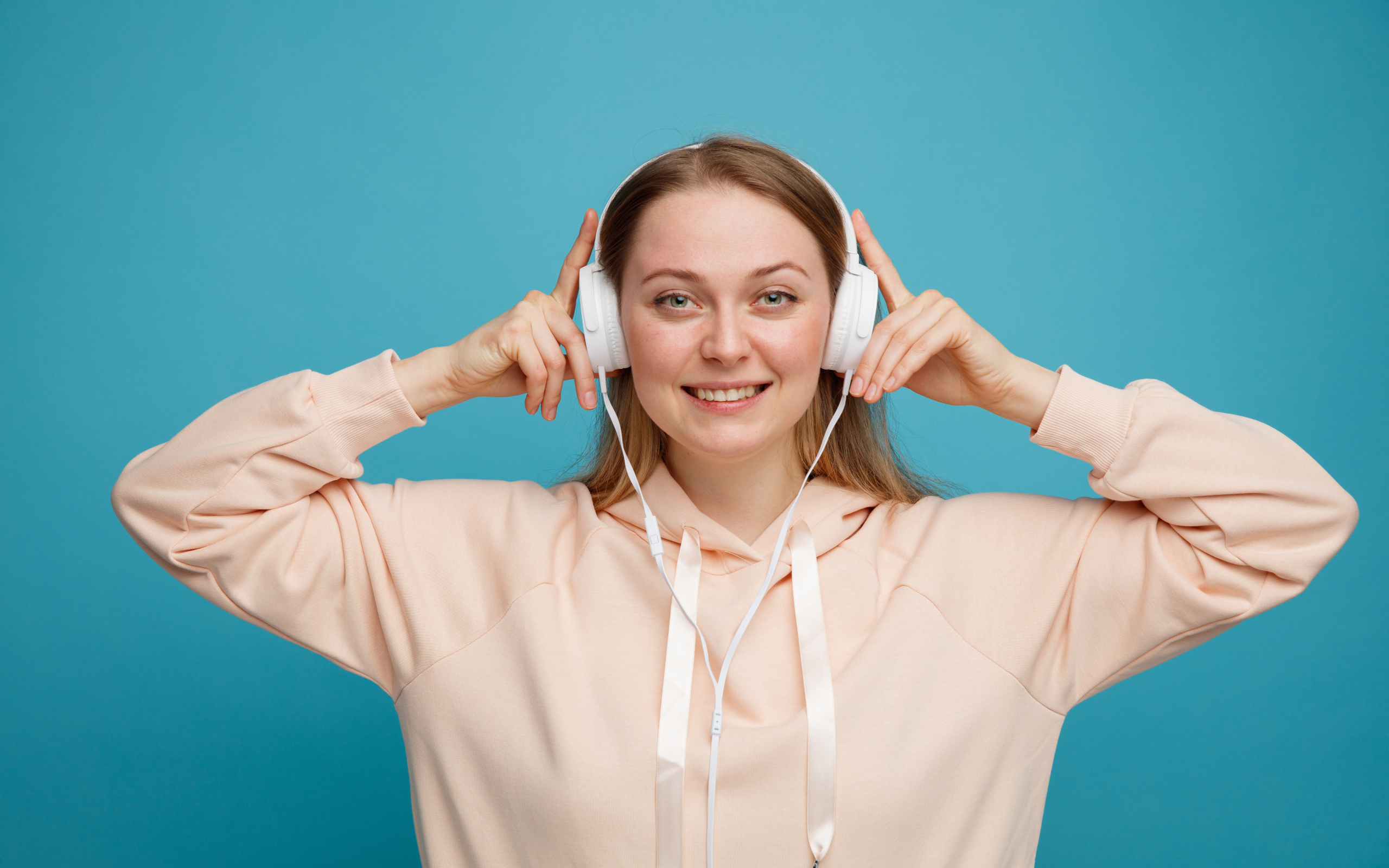 Улыбающаяся девушка в наушниках на голубом фоне