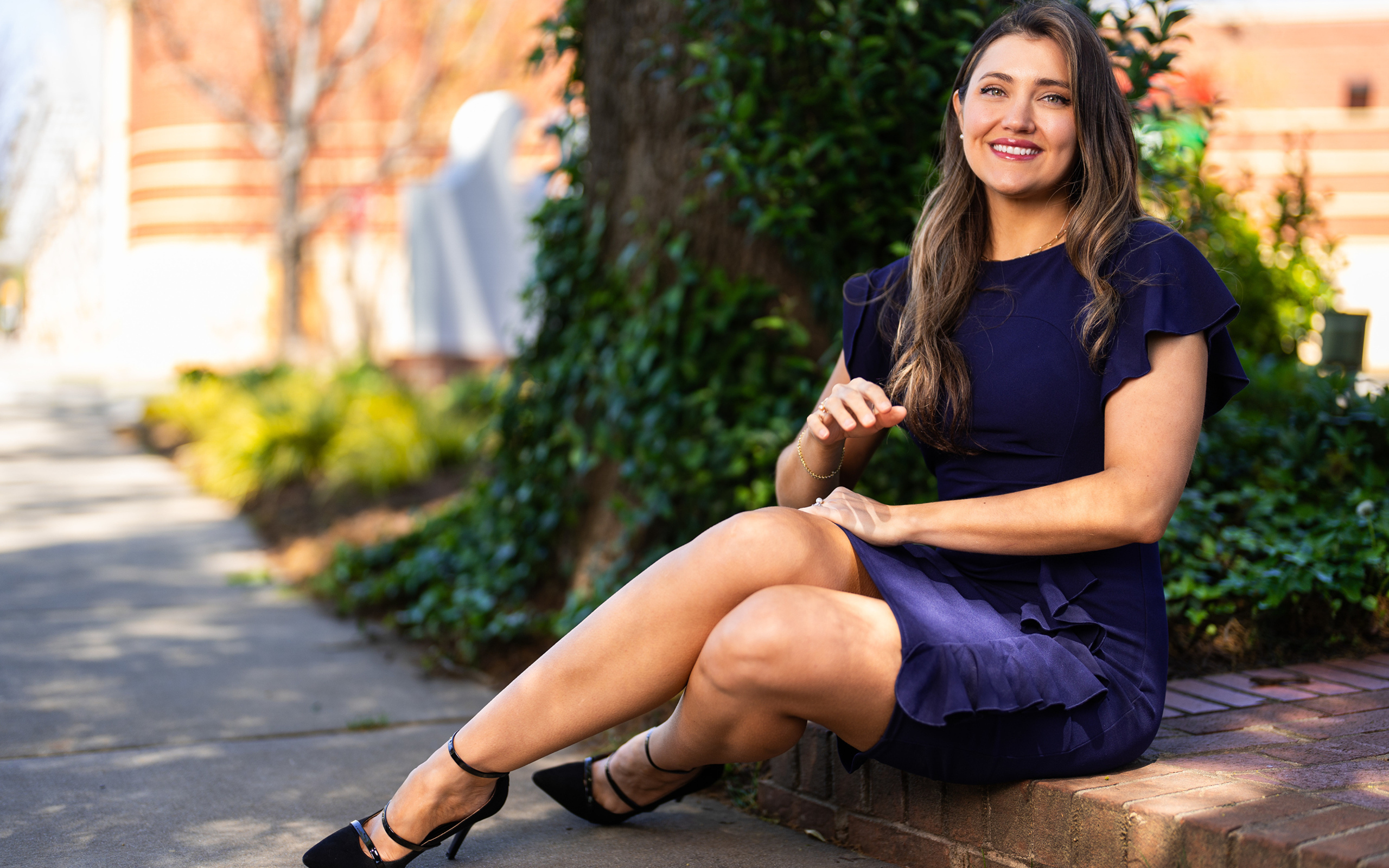 Улыбающаяся женщина в синем платье сидит на земле