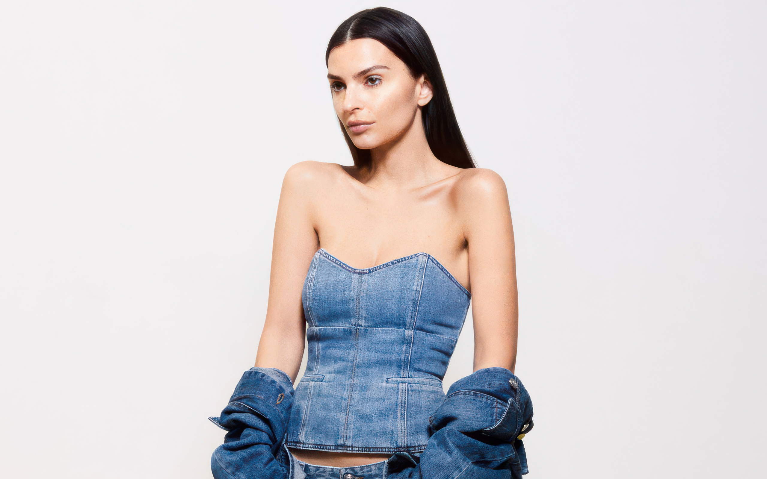 Модель Эмили Ратаковски в джинсовом костюме на белом фоне