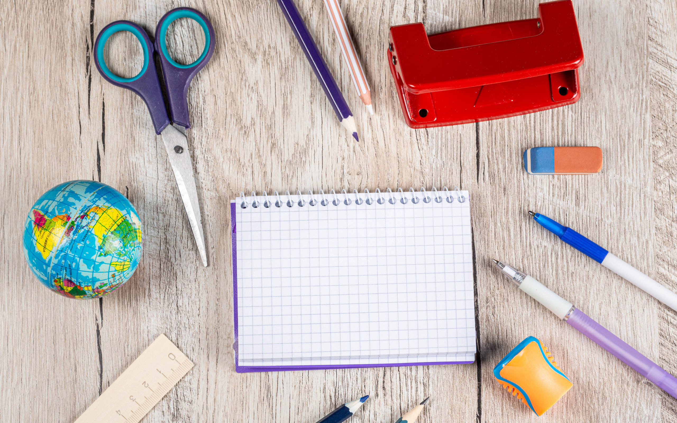 Канцелярские предметы, блокнот и глобус на деревянном столе