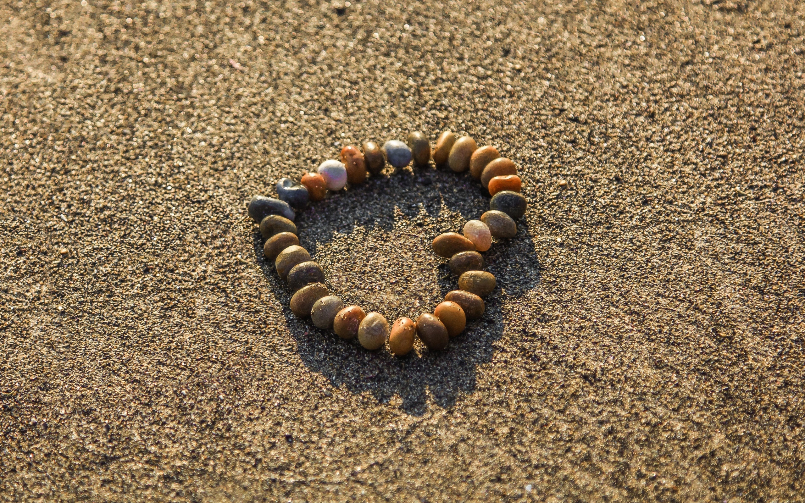 Сердце из камней на морском песке летом