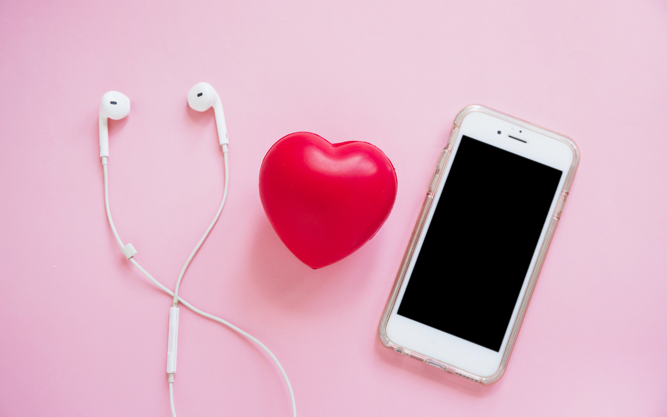 Телефон, наушники и красное сердце на розовом фоне