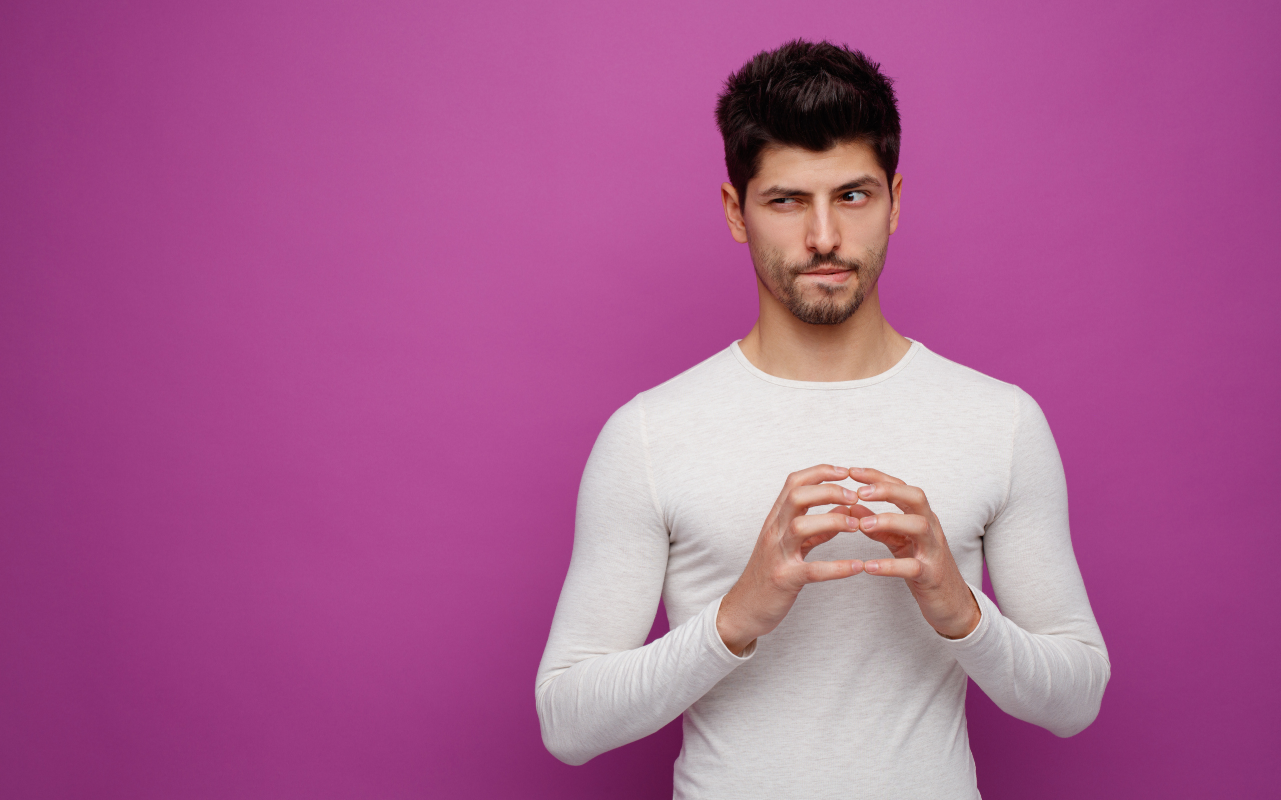 Хитрый мужчина в белом свитере на сиреневом фоне