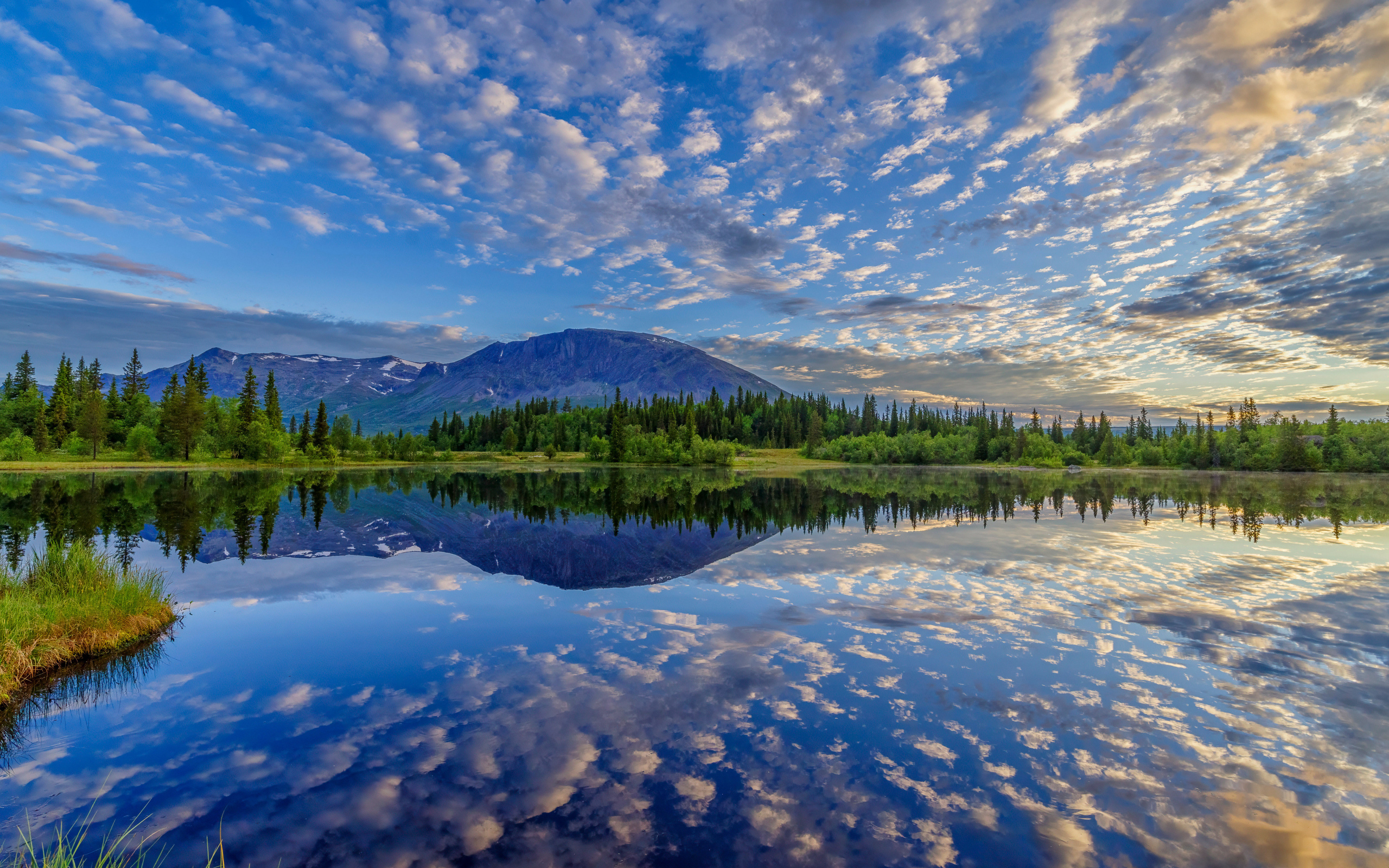 Красивое небо с облаками отражается в озере у гор