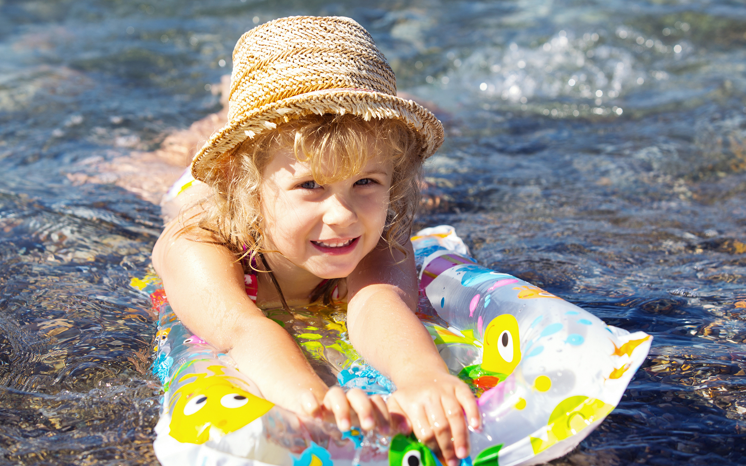 Девочка в шляпе плавает в воде