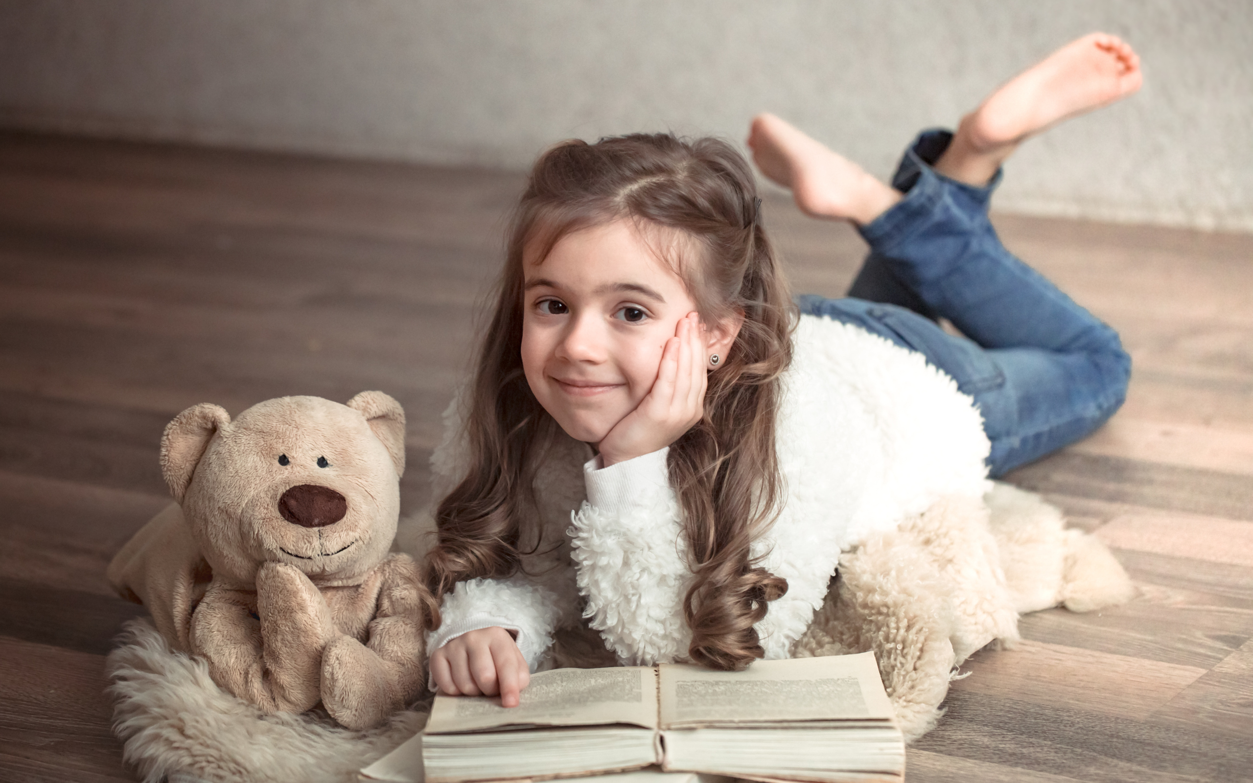 Девочка с медведем и книгой лежит на полу