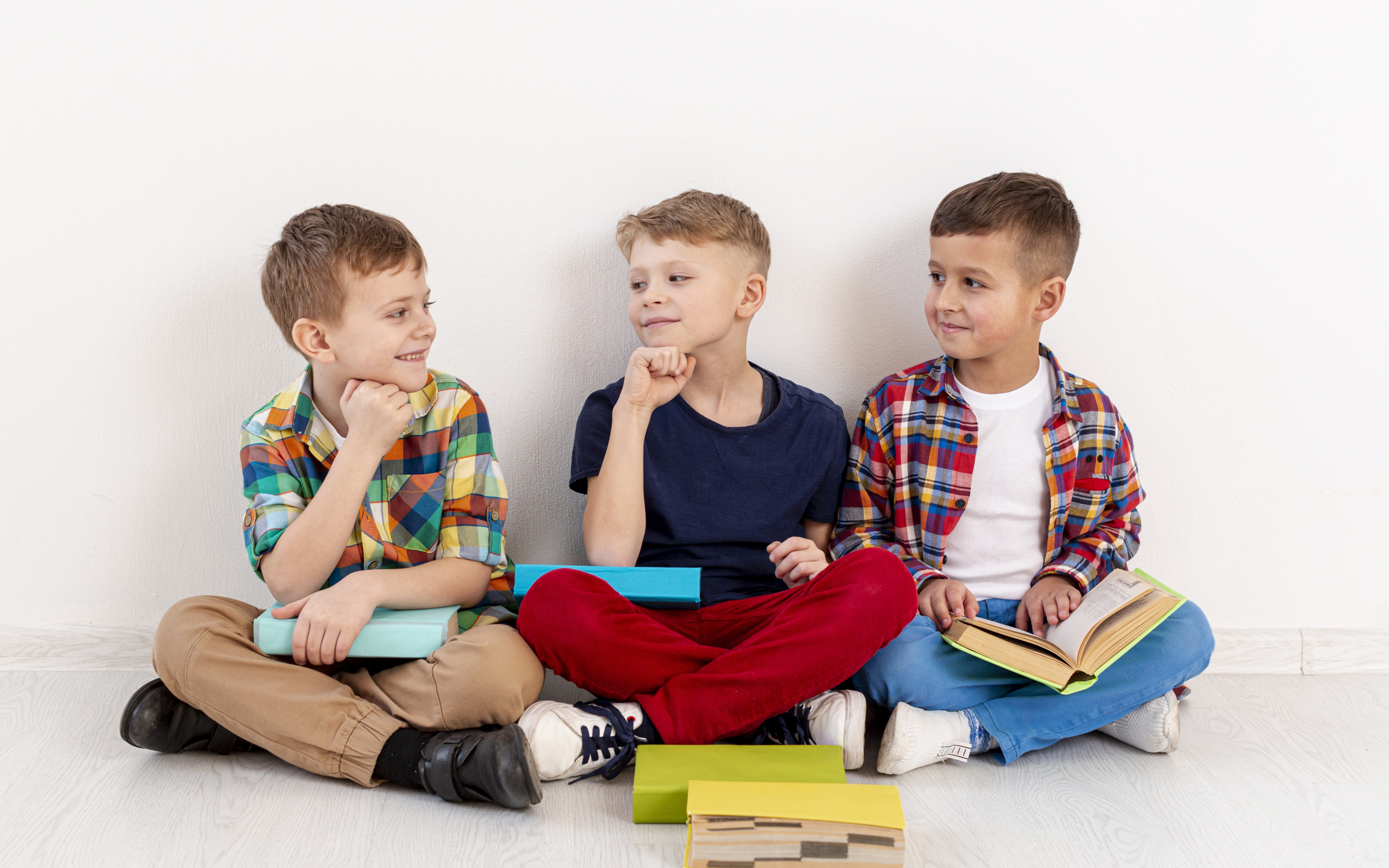 Три мальчика с книгами сидят у стены
