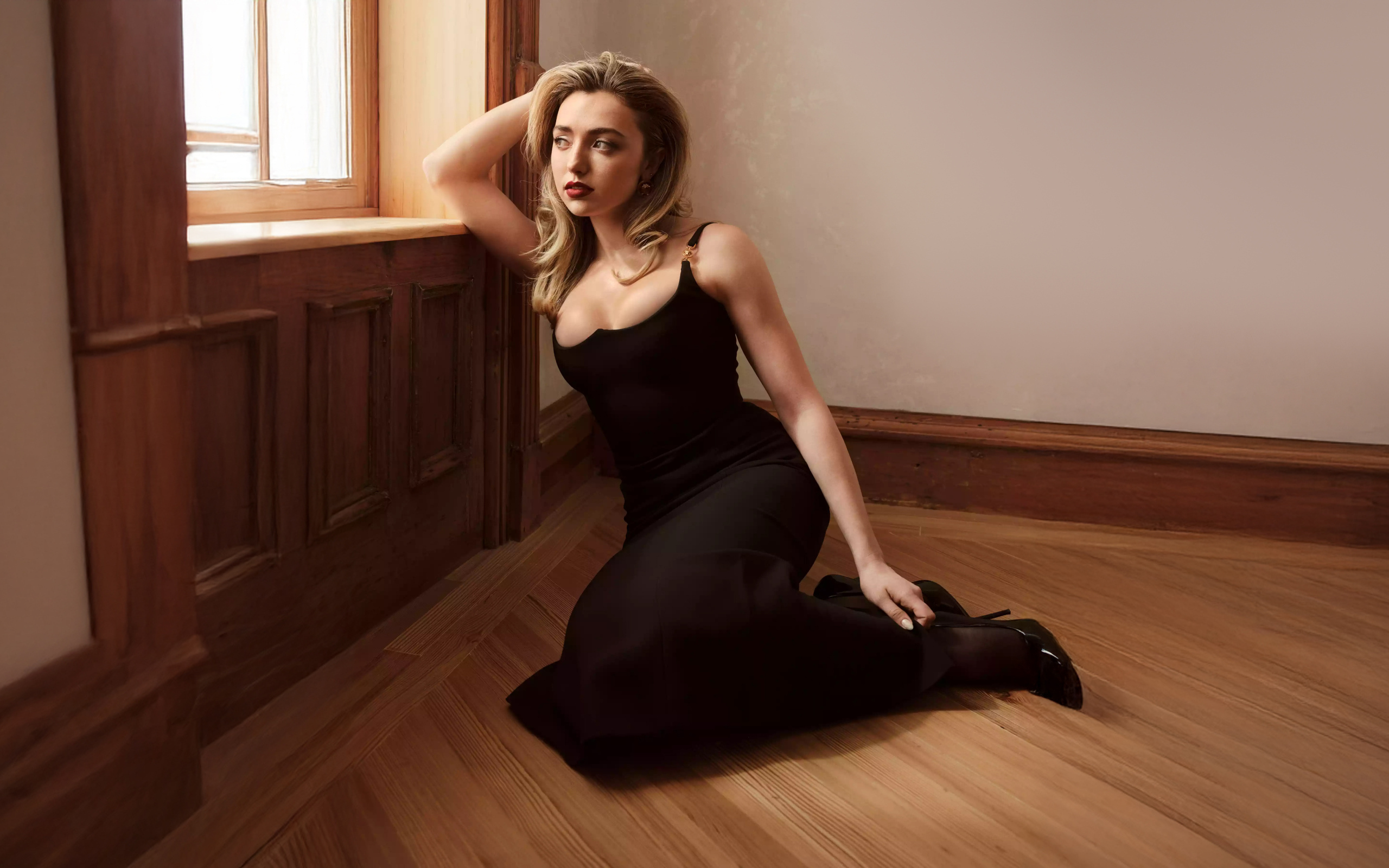 Актриса Пейтон Рой Лист в черном платье сидит на полу у окна