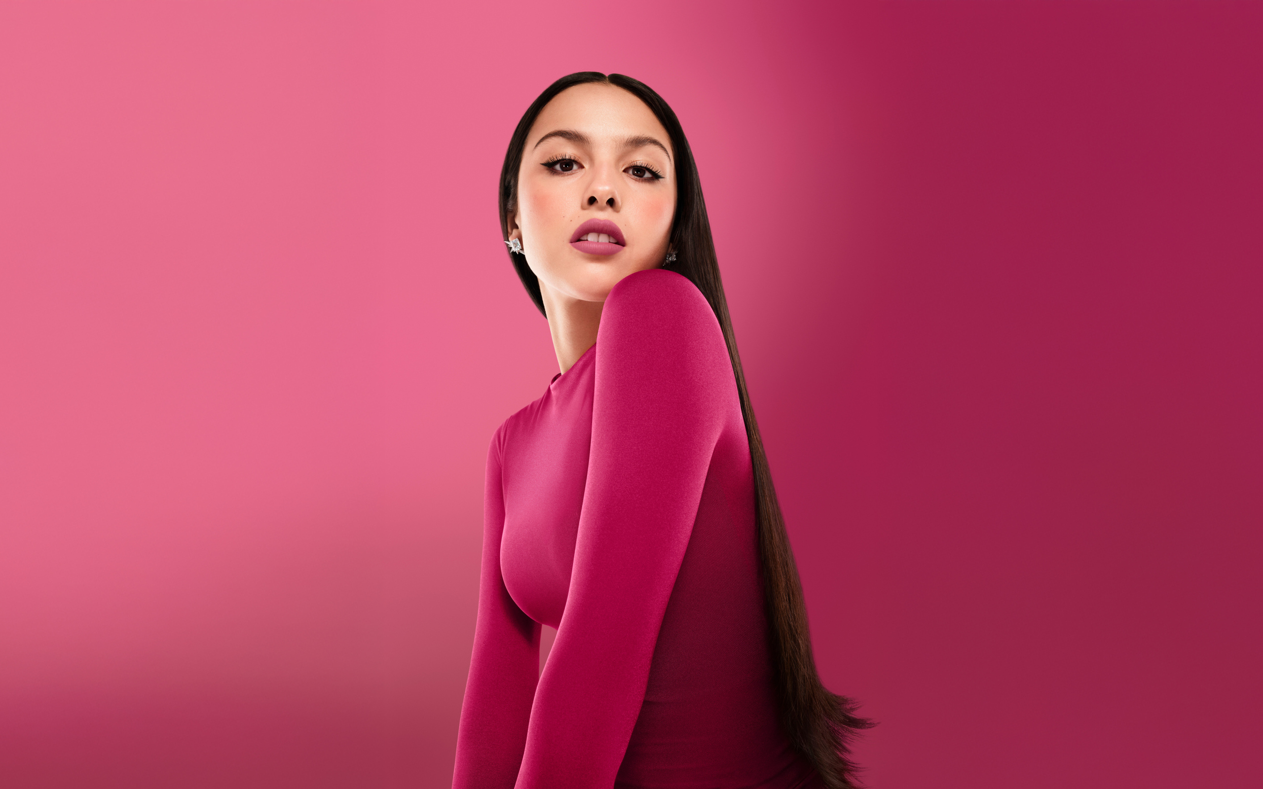 Длинноволосая актриса Оливия Родриго на розовом фоне