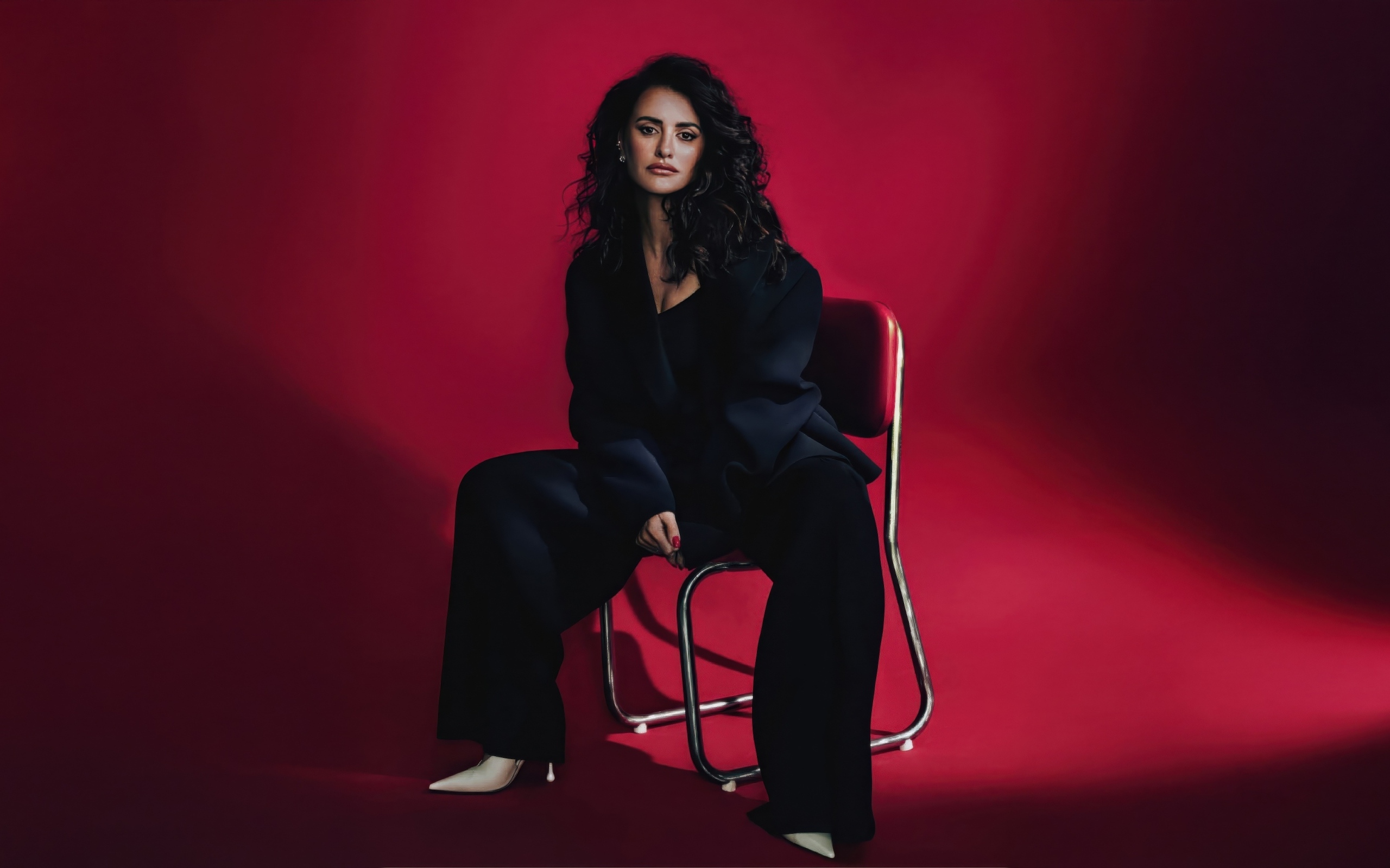 Испанская актриса Пенелопа Крус сидит на стуле на красном фоне