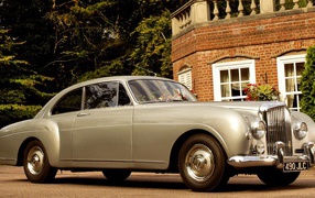 Белый автомобиль у кирпичного дома