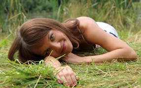 The girl smiles and lies on the grass