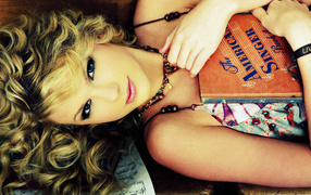 Taylor Swift лежа с своей гитарой