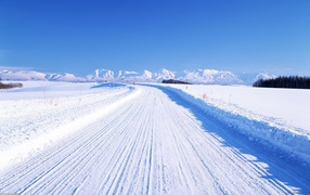 Winter road on a background of snow-capped mountains