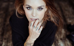 Brown-haired girl with a pierced nose and tattoos on arm