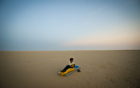 Мужчина на матрасе на пляже