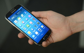 Samsung Galaxy S4 в руке на сером фоне