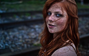 Девушка с веснушками на фоне рельс