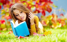 Девушка на траве читает книгу