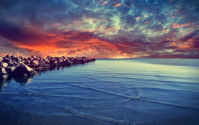 Красный закат над каменистым берегом