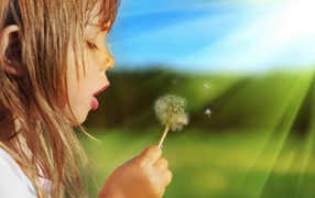 Девочка дует на одуванчик