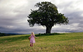 The little girl runs to the tree