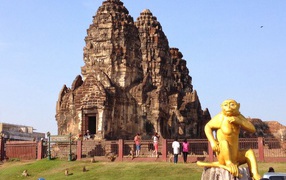 Золотая обезьяна на фоне храма на курорте Лопбури, Таиланд