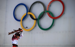 Биатлонист на фоне колец на Олимпиаде в Сочи